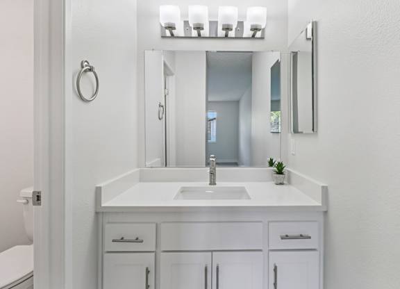 A white bathroom with a sink and mirror.