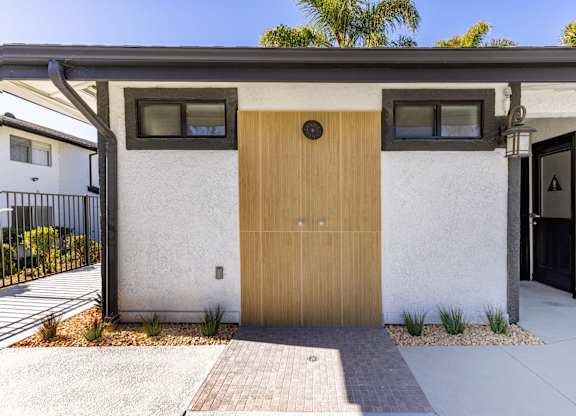 A modern house with a wooden front door and a black gate.