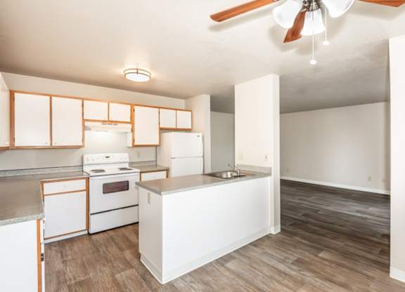 A kitchen with white appliances and wooden floors.