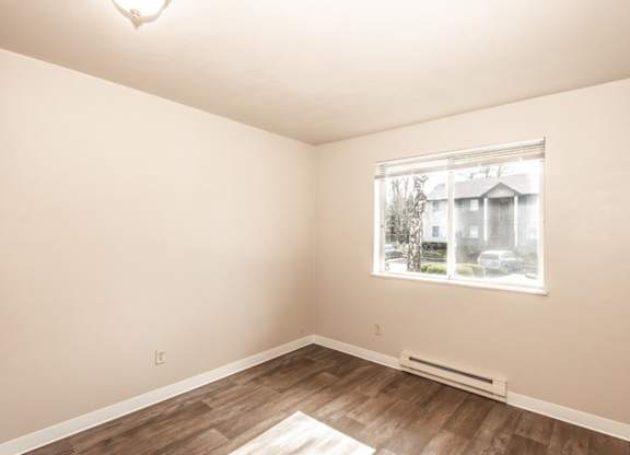 A room with a window showing a house and trees outside.