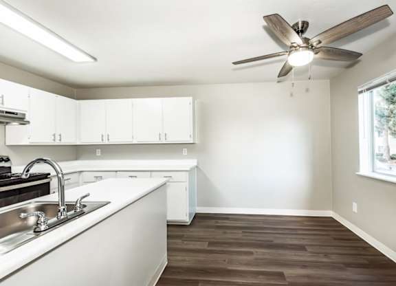 A kitchen with white cabinets and a wooden floor.