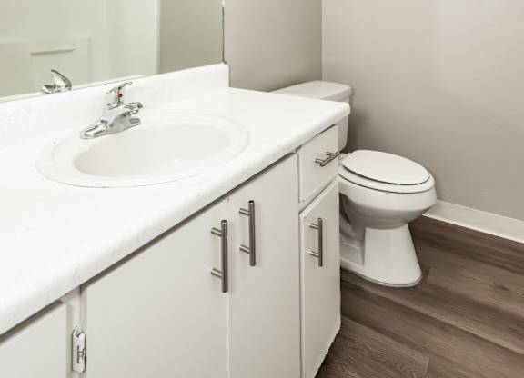 A white bathroom with a toilet, sink and mirror.