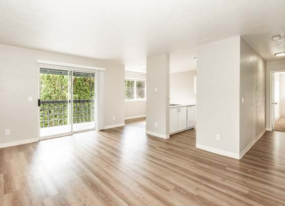 A spacious living room with wooden floors and white walls.