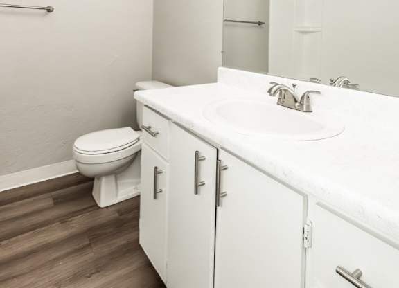 A white bathroom with a toilet, sink, and mirror.