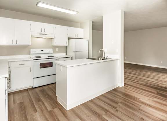 A kitchen with white appliances and wooden floors.