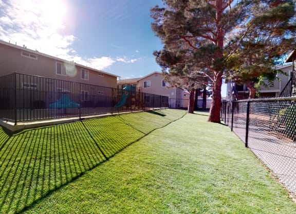Fenced-In Playground Next to Apartment Building Surrounded by Lush Landscaping at Aspire High Desert Apartments, Victorville, California