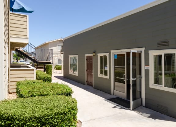 a side view of a gray building with doors and a sidewalk at Aspire High Desert Apartments, Victorville, 92392