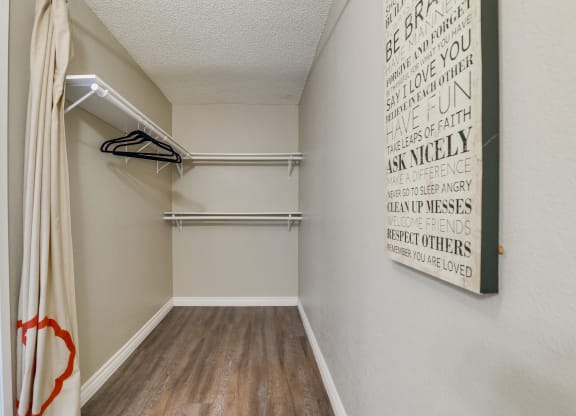 Walk-In Closet with Shelves and Hangers, Beige Walls, and Plank Flooring at Las Brisas Apartments, Colton, CA