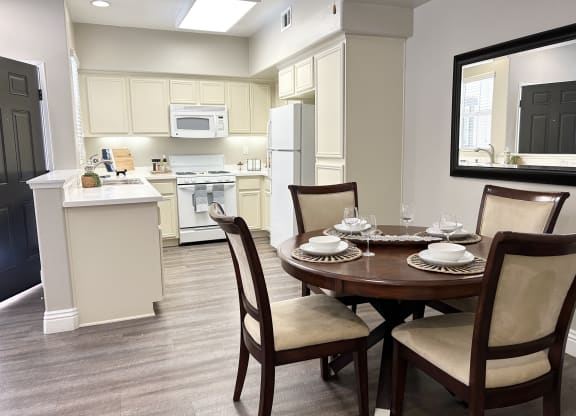 a dining area with a table and chairs and a kitchen in the background at Riverton of the High Desert Apartments, California, 92392