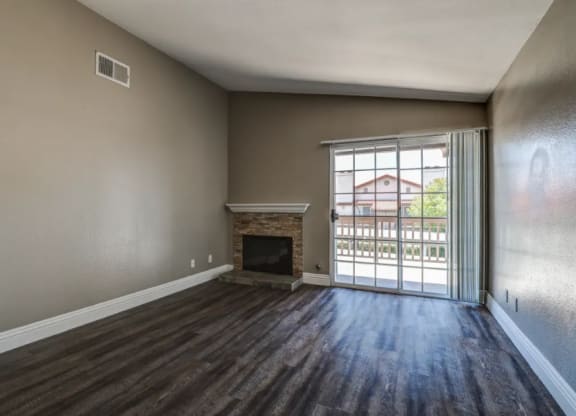 an empty living room with a fireplace and a sliding glass door at Vista Promenade Apartments, California
