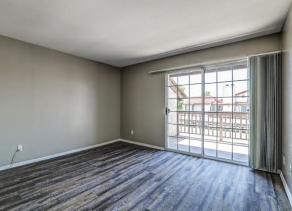 an empty living room with a sliding glass door to a balcony at Vista Promenade Apartments, Temecula, California