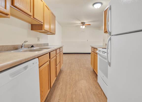A kitchen with wooden cabinets and white appliances. at Winding Hills Apartments, Davenport , Iowa