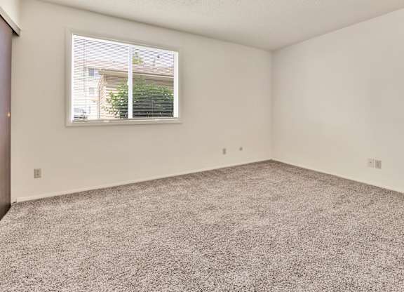 A room with a carpeted floor and a window. at Winding Hills Apartments, Iowa