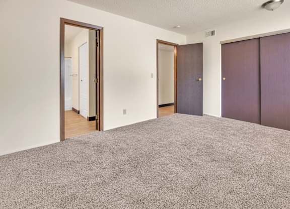 A room with a carpeted floor and two doors. at Winding Hills Apartments, Iowa, 52807