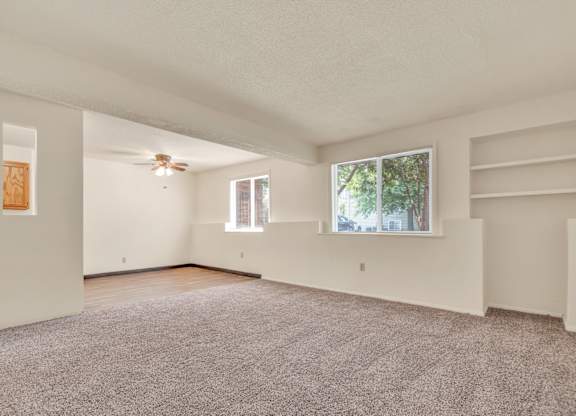 A spacious room with a ceiling fan and two windows. at Winding Hills Apartments, Iowa