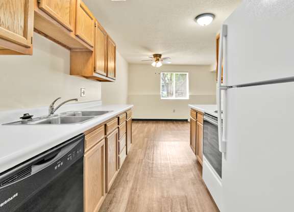 A kitchen with wooden cabinets and a black dishwasher. at Winding Hills Apartments, Davenport  52807