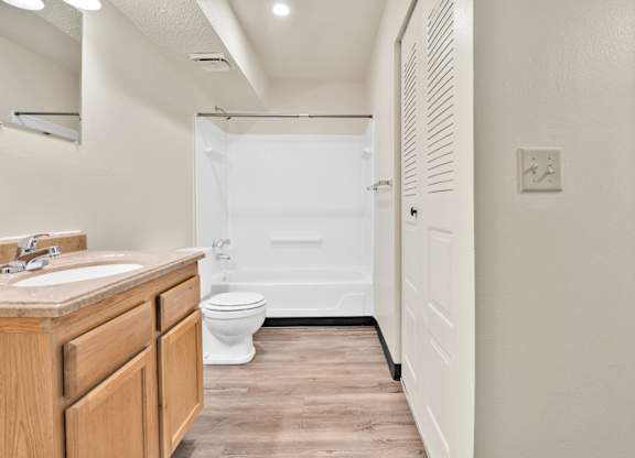 A white bathroom with a toilet, sink, and bathtub. at Winding Hills Apartments, Iowa, 52807