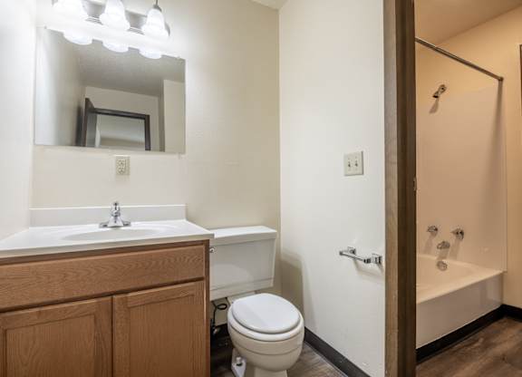 A bathroom with a toilet, sink, and mirror. at Winding Hills Apartments, Davenport , Iowa