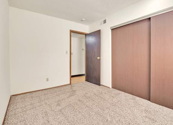 A room with a carpeted floor and two brown doors. at Winding Hills Apartments, Davenport  52807