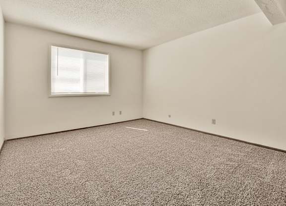 A room with a carpeted floor and a window. at Winding Hills Apartments, Davenport , IA