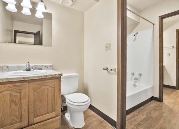 A bathroom with a toilet, sink, and mirror. at Winding Hills Apartments, Davenport , Iowa