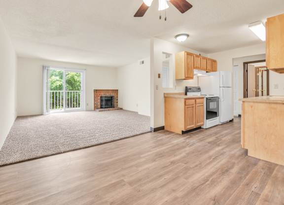 A living room with a fireplace and a kitchen area in the background. at Winding Hills Apartments, Davenport , IA, 52807