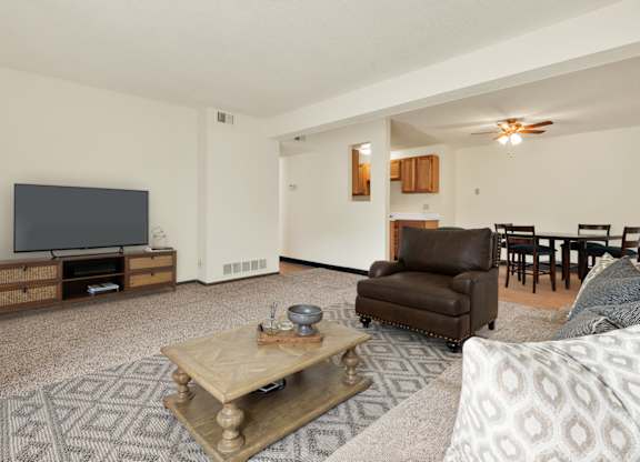 A living room with a brown leather chair and a wooden coffee table. at Winding Hills Apartments, Davenport , Iowa