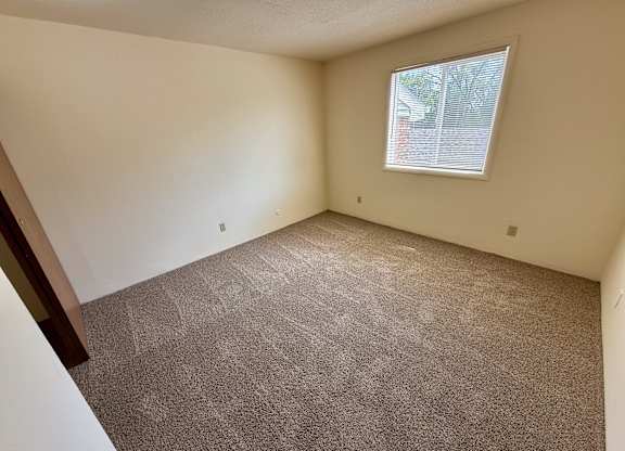 A room with a carpeted floor and a window. at Winding Hills Apartments, Davenport