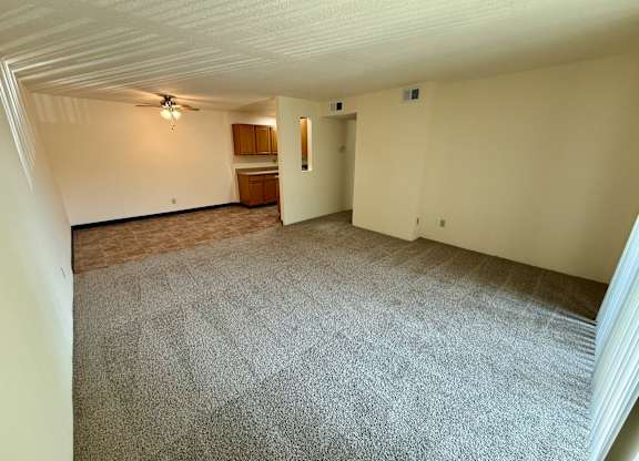 A room with a carpeted floor and a ceiling fan. at Winding Hills Apartments, Davenport  52807
