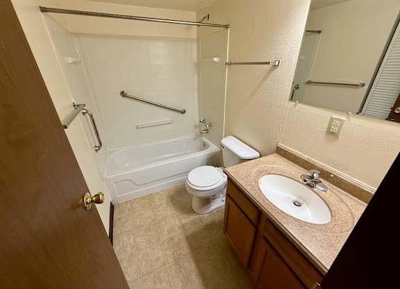 A bathroom with a toilet, sink, and bathtub. at Winding Hills Apartments, Iowa, 52807