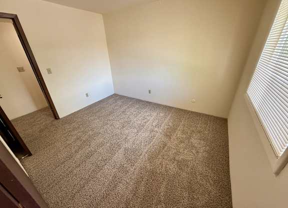 A room with carpeted floor and a window with blinds. at Winding Hills Apartments, Davenport , IA