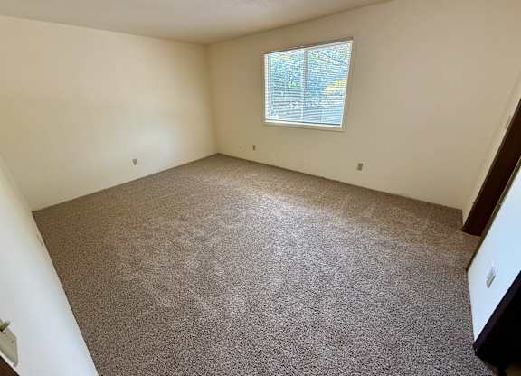 A room with a carpeted floor and a window. at Winding Hills Apartments, Davenport , Iowa