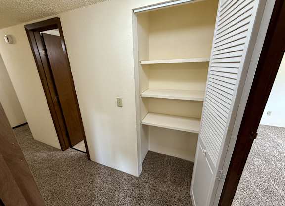 A white closet with three shelves is open. at Winding Hills Apartments, Davenport , IA, 52807