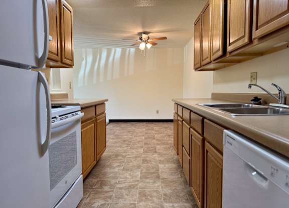 A kitchen with a white refrigerator, a white dishwasher, and wooden cabinets. at Winding Hills Apartments, Davenport , IA