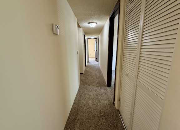A long hallway with a carpeted floor and white walls. at Winding Hills Apartments, Davenport , IA
