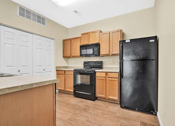 A kitchen with a black refrigerator, oven, and microwave. at Deer Valley Apartments, Illinois, 61282