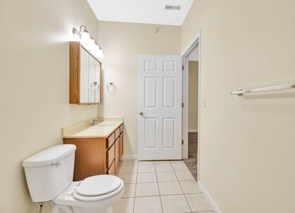 A white toilet sits next to a sink in a bathroom. at Deer Valley Apartments, Silvis, Illinois