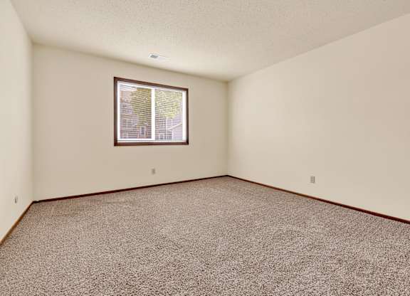 A room with a carpeted floor and a window.at Windsor Crest Apartments, Davenport 52807