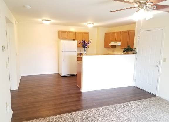 A kitchen with a white refrigerator and wooden cabinets.at Windsor Crest Apartments, Davenport