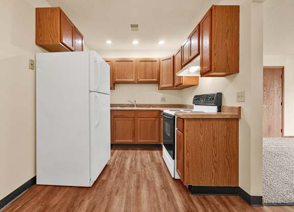 A kitchen with wooden cabinets and a white refrigerator.at Windsor Crest Apartments, Iowa