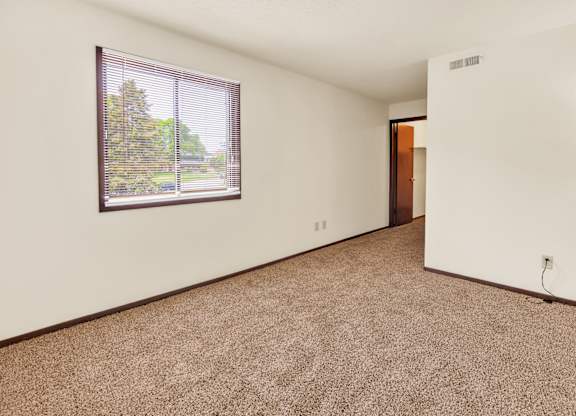 A room with a window and a carpeted floor. at Indian Ridge Apartments, Iowa, 52807