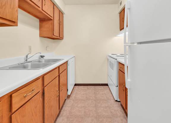 A kitchen with white appliances and wooden cabinets. at Indian Ridge Apartments, Davenport, IA, 52807
