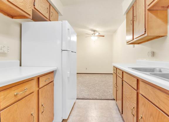 A kitchen with wooden cabinets and a white refrigerator. at Indian Ridge Apartments, Davenport, IA