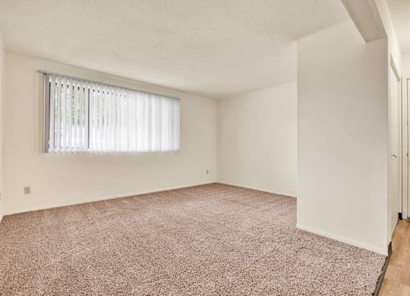 A room with a carpeted floor and a window with blinds. at Indian Ridge Apartments, Davenport, IA, 52807