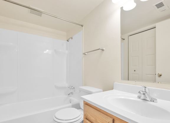 A white bathroom with a toilet, sink, and bathtub. at Indian Ridge Apartments, Davenport, IA, 52807