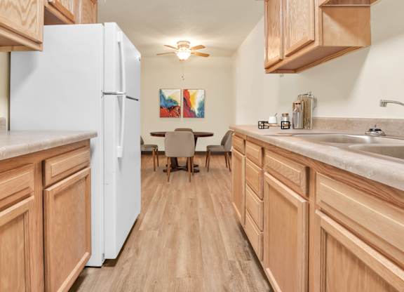 A kitchen with wooden cabinets and a white refrigerator. at Indian Ridge Apartments, Davenport, IA