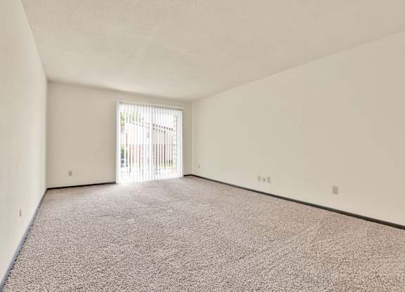 A room with a carpeted floor and a sliding glass door. at Indian Ridge Apartments, Davenport