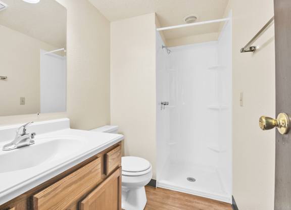 A white bathroom with a toilet, sink, and shower. at Indian Ridge Apartments, Davenport