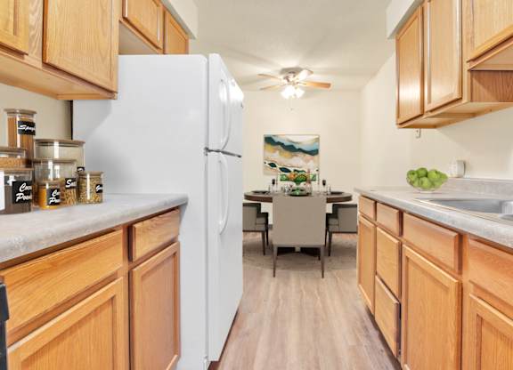 A kitchen with wooden cabinets and a white refrigerator. at Indian Ridge Apartments, Davenport