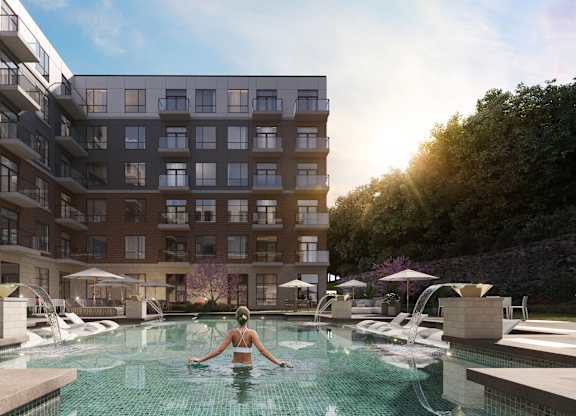 A woman is swimming in a pool surrounded by apartment buildings at The Woods at 180 Kanata Avenue, Kanata, K2K 3L9